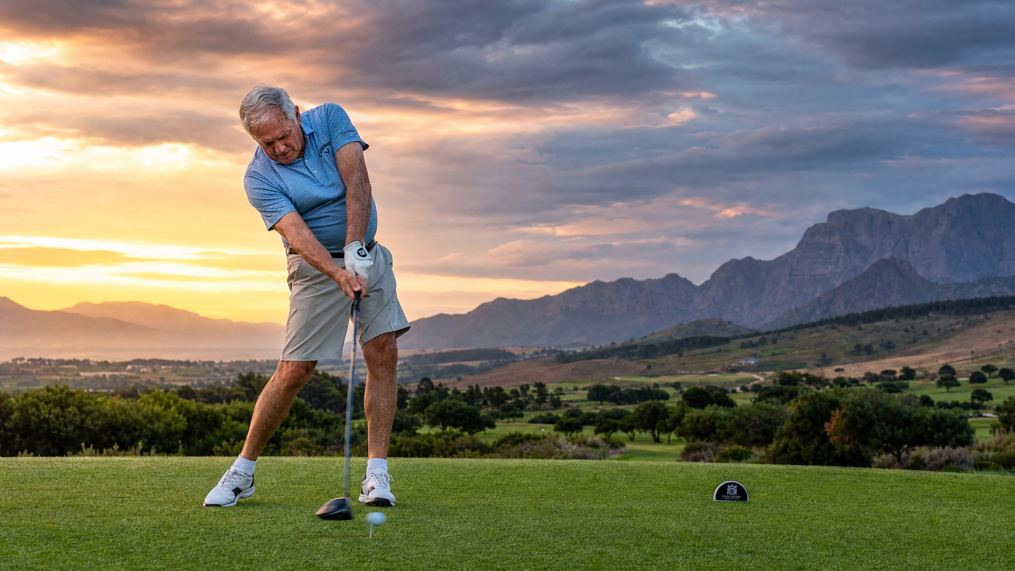 Senior golfer mid-swing on scenic course